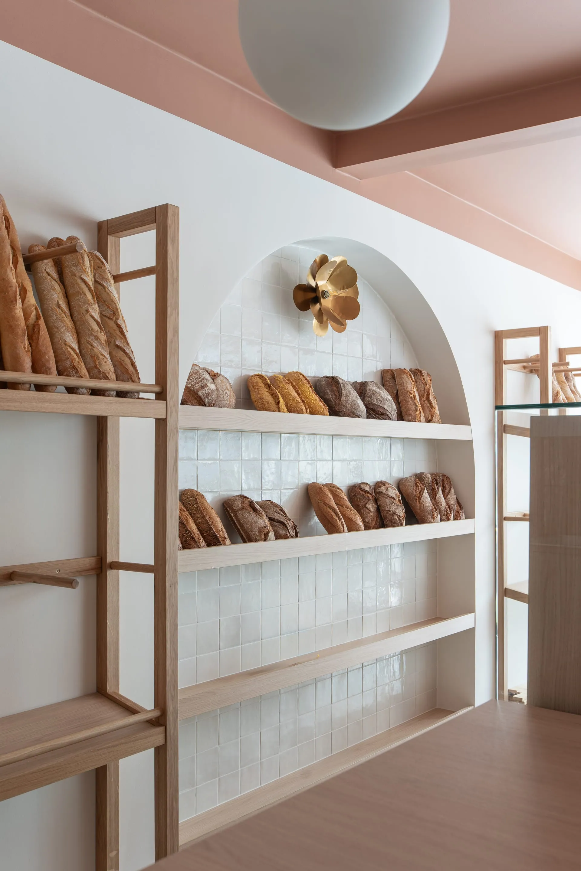 Étagères à pain en bois clair sous une niche cintrée, boulangerie Le Coin des Gourmands à Chagny
