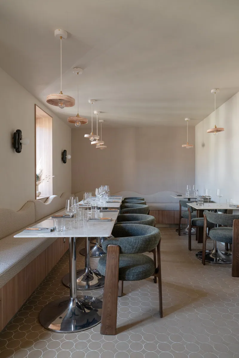 Salle du restaurant Papi à Chassagne-Montrachet : banquette le long du mur, tables et chaises vert sauge